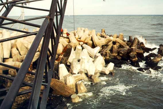 Figure 7.13. Core-loc Armor Units on Manasquan Jetties being placed over dolos. (The darker units are dolos.) 7.3.5 Groins A groin is a relatively slender permeable or impermeable barrier structure aligned and constructed to trap littoral drift or retard erosion of the shore.