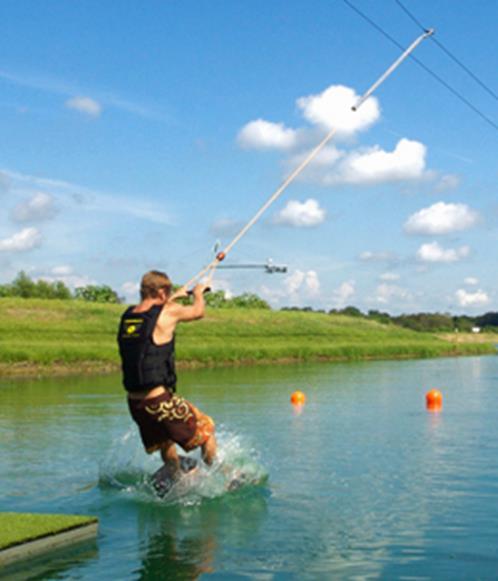 A wake park includes a lake being surrounded by masts which hold an overhead cable.