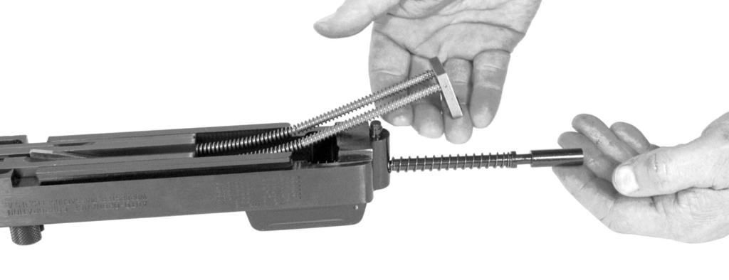 While the receiver is still upside down, the internal parts of the receiver can be removed by pulling up on the recoil spring guide and springs.