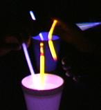 [Turns light on and removes cups of hot water from tables. Holds up a different kind of glow stick.] This kind has quite a bit more chemical in it.