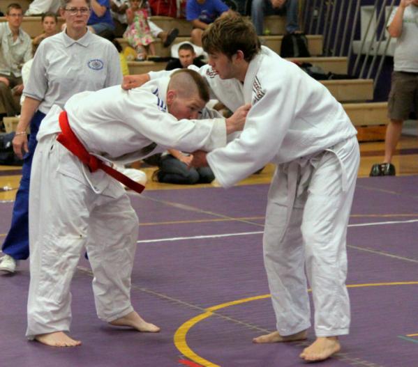 One athlete wears a red belt and one athlete wears a white belt.