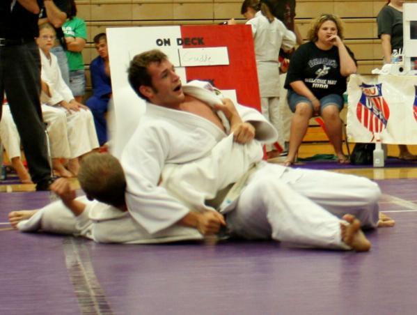 Referee Sandi Harrellson watches closely as two athletes compete. Notice one wears a red belt and the other wears a white belt.