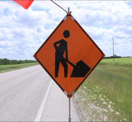 The "Roadwork Ahead" warning sign is diamond shaped with black letters on a reflective orange background.