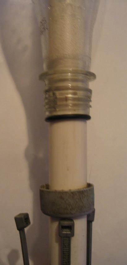 The arrangement of the bottle, the sealing O ring and the modified cap used to clamp the O ring against the launch tube. Far Right.