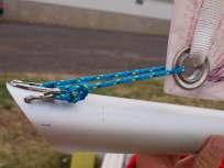 Depending on how the main sail has been rolled, it may be required to unroll it completey Attach the ring and shackle to the eyelet at the head of the main sail and ensure that the halyard is between