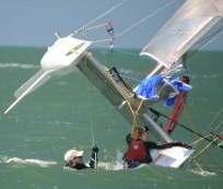 Climb up onto the hull as soon as possible and release the downhaul, mainsheet, traveler, jib sheet and spinnaker sheet.