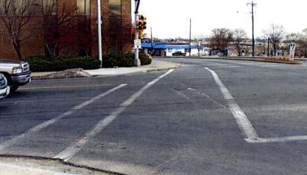Pedestrian crossings are striped across all four approaches, with only simple, parallel white stripes; each corner features only one sidewalk curb cut for wheelchair ramps.