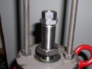 In order to completely relieve the spring, the two nuts per threaded rod are evenly turned upwards until the spring bonnet is loose.