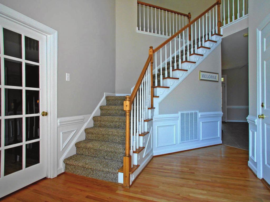 Dramatic, two-story foyer provides a beautiful introduction to the home, complimented by: Gleaming hardwood floors Open, curved staircase Neutral paint Wainscoting