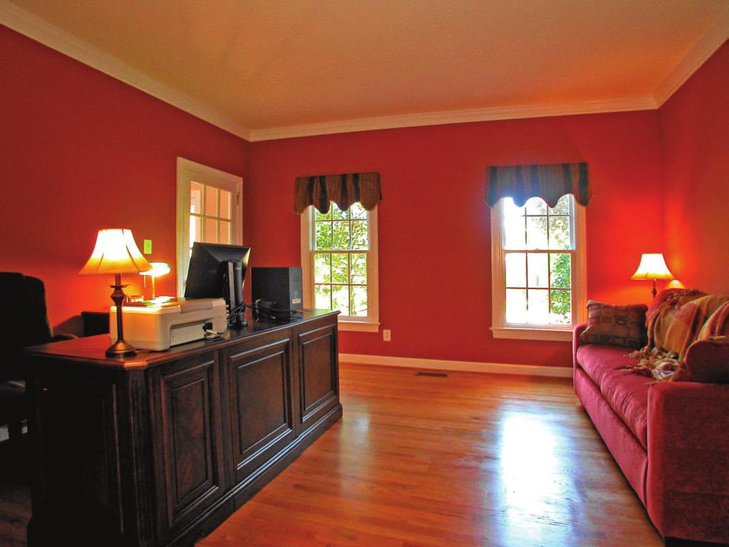 of the foyer, a spacious and sunny living room (currently used as a study/home office), featuring: Warm hardwood floors Framed, French-style double windows Crown