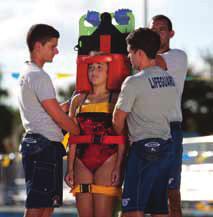 At the beginning, this lifeguard stands behind the board and reaches around to