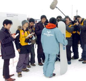 An athlete being interviewed by the media after a Snowboarding event.