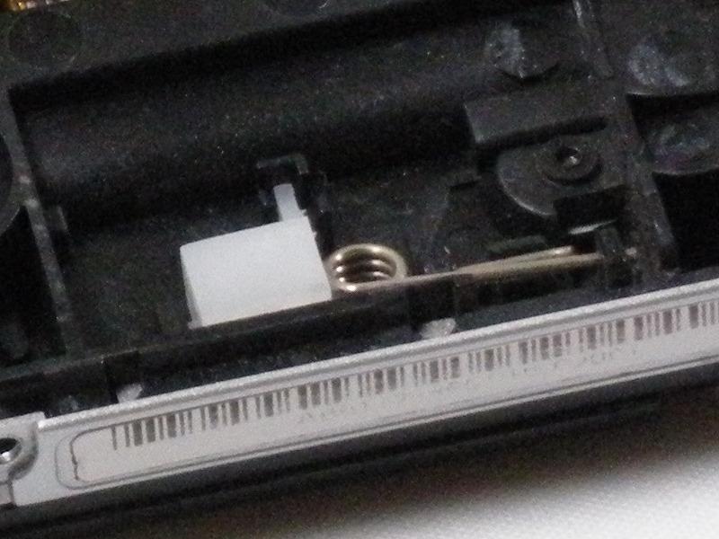 Step 9 With the front side of the PSP facing you, locate small white plastic box with metal spring attached.