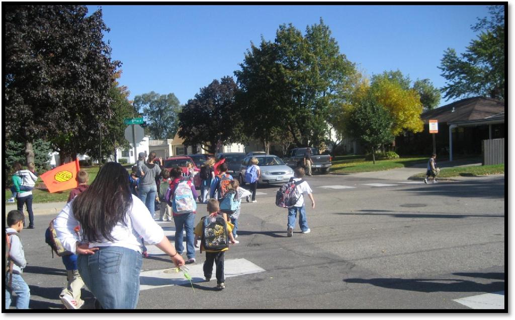 Group of students crossing with student patrols at the 3rd Street N/9 th Avenue intersection after school.