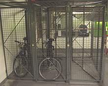 Bike cages or locked rooms that accommodate multiple bicycles are common at workplaces. They usually contain bike racks within the fenced cage or locked room as additional security.