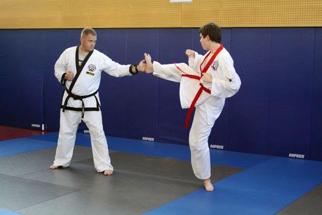 Senior shifts (slides) backwards without switching stances feeding front-side open hand target with finger tips orientated at partner receiving Doolgae Cha Ki (Tornado crescent kick).