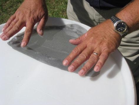 Cut fiberglass screen into a section at least 1 greater than the hole at the