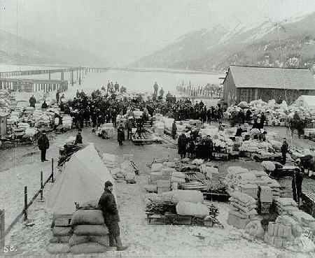 Skagway and Dyea: Gold Rush BoomTowns Outfits lay stacked in Dyea as stampeders grouped their supplies. Circa 1897.