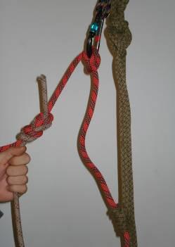 (a) Begin by establishing a lower appropriate to the load. The no-hands backup should be tied on the load side of the rope instead of the brake side.