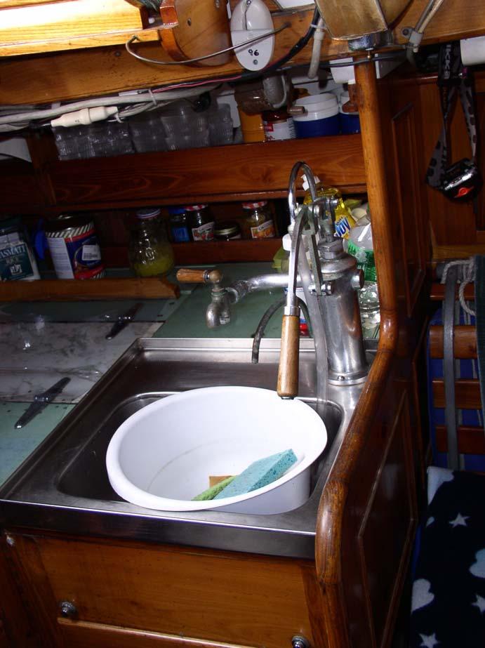 The port side of the galley includes a fitted stainless sink with a large manual pump.
