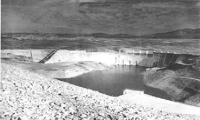 Figure 9. Hogan Dam, showing water outlet holes. The dam is shown upstream behind New Hogan Dam, under constructin in the foreground. Calaveras River.
