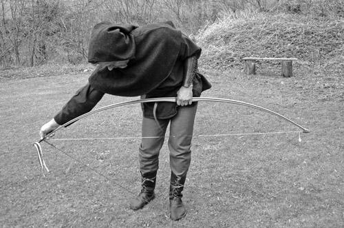 The lower limb of the bow is placed over the archer s left foot and the bow s grip behind the archer s thigh. Using both hands, the archer pushes the upper limb forward and slides the loop into place.