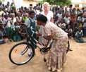 You will then pick up your bicycle and ride to a school in a typical rural district tall grasses, dirt roads, villages with mud huts, thatched
