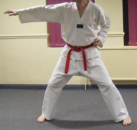 Step the right leg out to the side and bend the knees into a sitting stance whilst performing a knifehand strike.