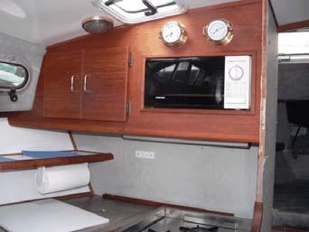 Aft lower galley. Fridge to left, three-burner stove to right, sink between. Above-galley storage.