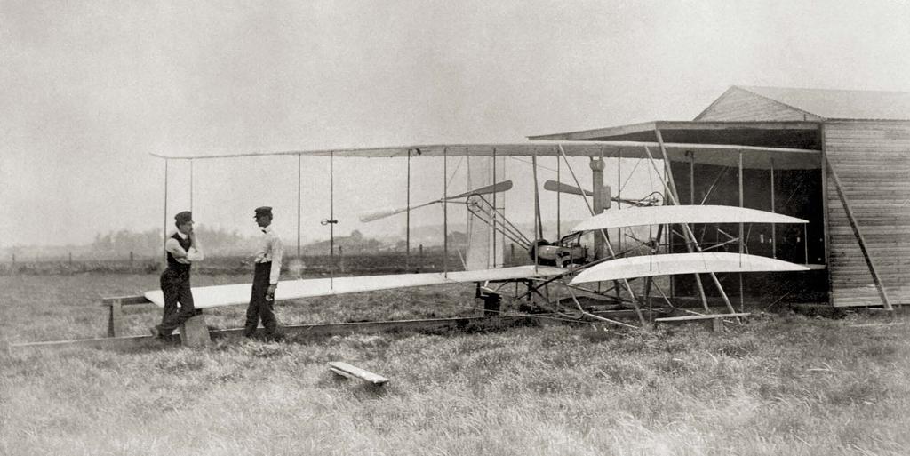 Wilbur and Orville Wright standing alongside one of their