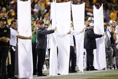 Oregon coaches use sheets to block the view of signal callers on the team bench during a game against Arizona State this season. that can include the formation, the cadence and even the play.