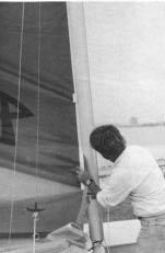 With one hand, feed the curf and pull on rope tail of halyard with the other.