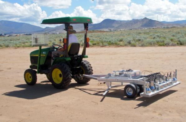 Fig. 3. Eight detector array and associated electronics pulled by tractor. The John Deere 4010 tractor has a hydrostatic transmission allowing the trailer to be pulled at a rate of 10 cm per second.