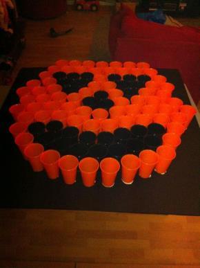 Title: Pumpkin Pong Items needed Example How to play: One player at a time will have 5 chances to shoot a ping pong ball into a red solo cup that will have a prize(candy/toy) in it.