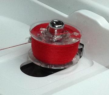 Proceed with winding the bobbin, either by pressing the foot control all the way down, or by unplugging the foot control and pressing the START/STOP button. Once the bobbin stops turning, itʼs full.