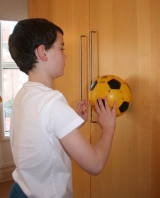 Using both hands together, but moving them in a walking motion, he must walk the ball up the wall until the centre of the ball is just above shoulder level.