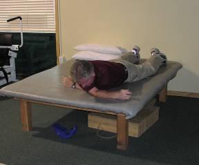 Lie flat on your stomach. Take your right arm and reach underneath you body to the left as far as you can reach.
