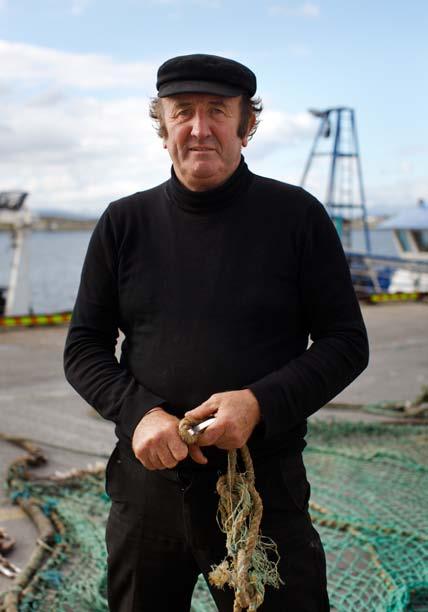 Captain of the Glor Na dtonn, a twin rig prawn trawler mending the trawl on the dock in Rossaveal, Ireland.
