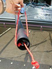Feed the 4mm line from the rigging box labeled boom through the small hole in the end of the boom and secure with a stopper
