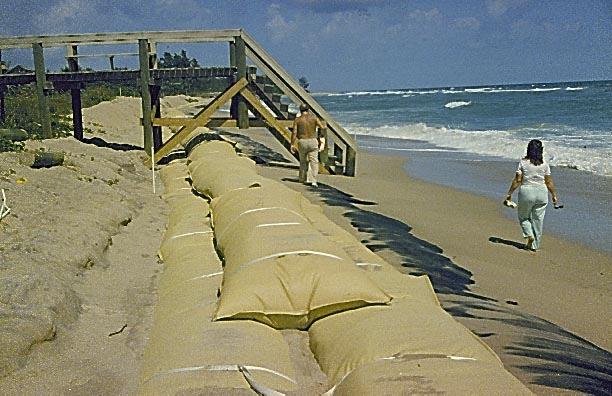 This phenomenon allows the sand to move around inside the containers, moving away from the strap encircled areas, thereby loosening the straps and allowing individual containers to be displaced, as