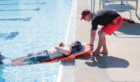 The rescuing lifeguard moves to the foot end of the board while the assisting responder holds the backboard at the head of the board from the pool deck.