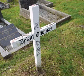 Walk straight down the hill from the gate between graves until you come to a white cross. This is the grave of Dylan and Caitlin Thomas.