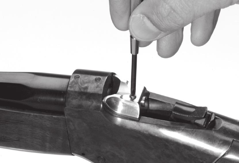 Remove the firing pin retaining screw by lifting it up, out of the hole in the top of the breech block. The firing pin is under spring force and may be lost if not carefully retained during removal.