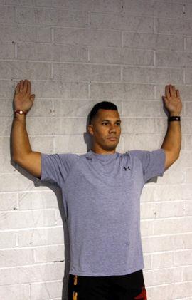 External Rotation / Anterior Mobility The athlete leans against the wall. Head, upper, mid, and lower back all make contact with the wall.