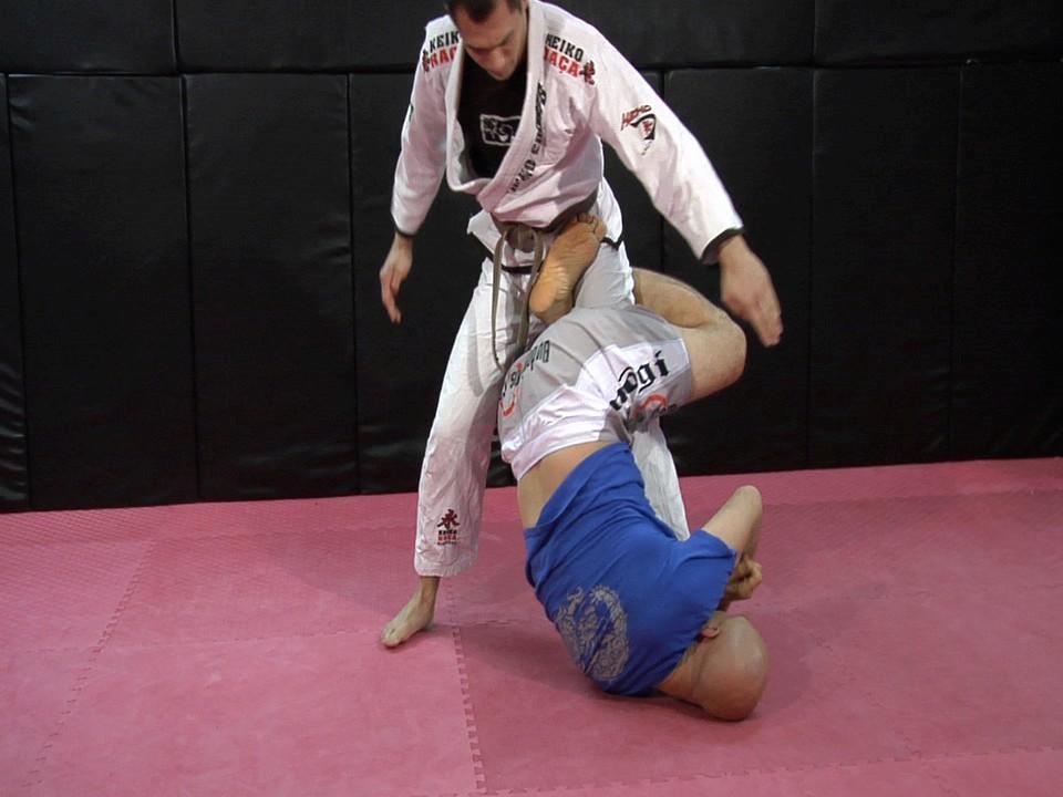 As part of his defense against the armbar, Ritchie stands up. I underhook his left leg with my right arm.