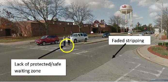 Figure E-33 illustrates the lack of pedestrian refuge islands as well as faded pavement markings that need replacement. Figure E-33. Faded marking and lack of refuge island at US Business 51 and W.