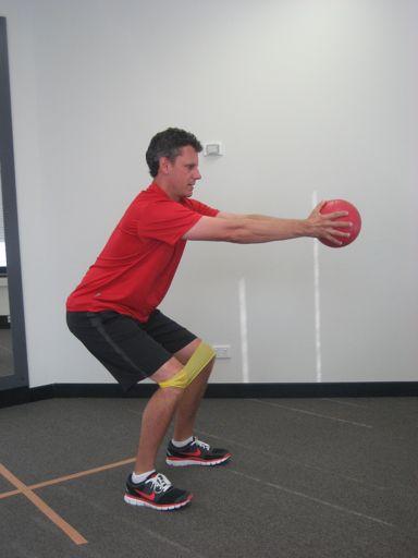 holding a light weight or medicine ball in front of them.
