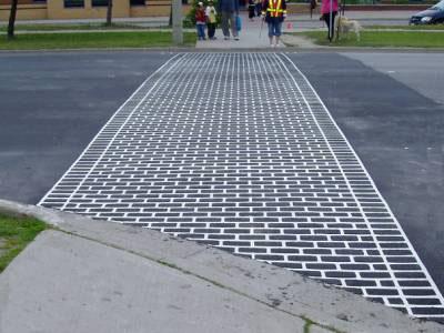 incorporating a textured and/or stamped surface which contrasts with the adjacent asphalt roadway.