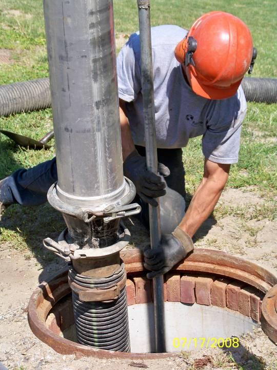 A maintenance worker stationed on the surface uses a vacuum hose to evacuate water, sediment, and debris from the system.