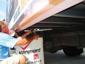 Move to the front of the truck body and attach the front strap to the longitudinal van body frame beam and take up some tension on this ratchet.